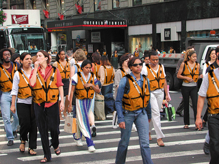 Life-jacketed pedestrians cross a busy intersection in Manhattan.
